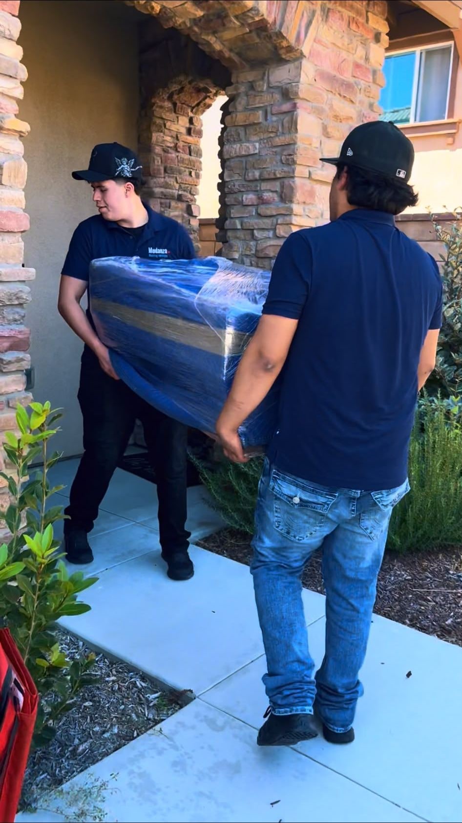 San Diego movers in blue uniforms safely transporting a heavy, protected item during a local home move.